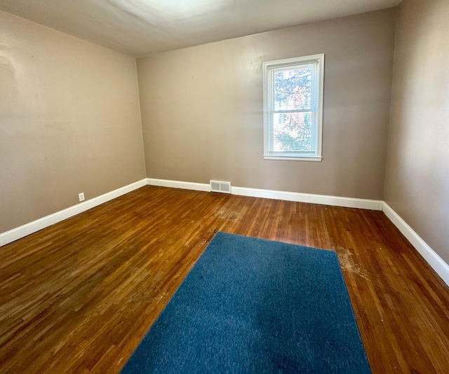 unfurnished room featuring visible vents, baseboards, and wood finished floors