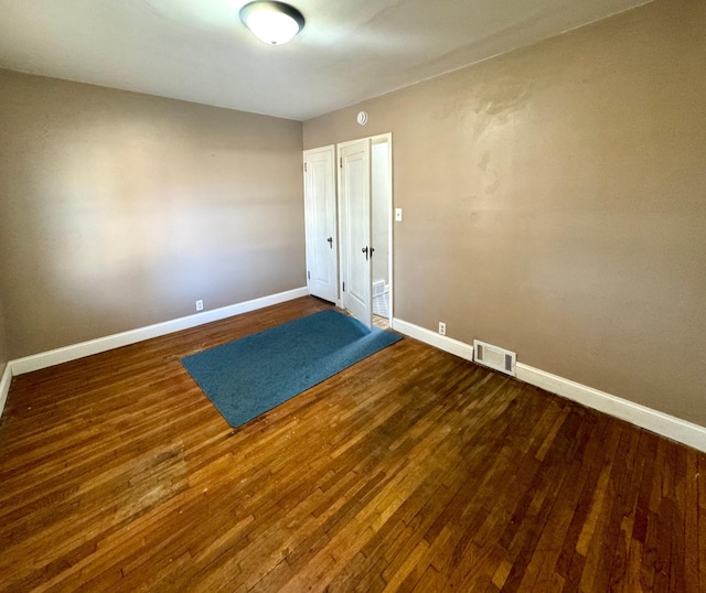 spare room with visible vents, baseboards, and wood finished floors