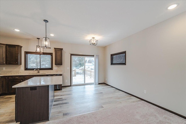 kitchen featuring hanging light fixtures, a kitchen island, sink, and dark brown cabinetry