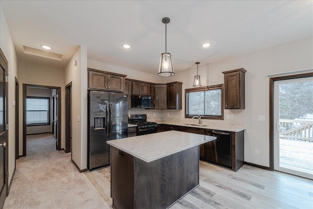 kitchen with pendant lighting, sink, a center island, dark brown cabinetry, and black appliances