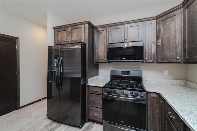 kitchen featuring light wood-type flooring, dark brown cabinets, range with gas stovetop, and black fridge