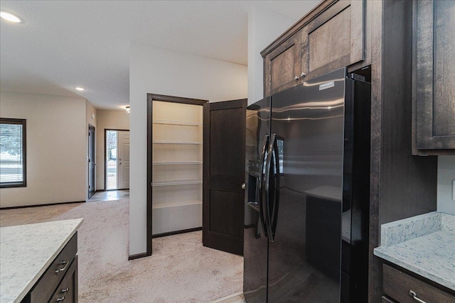 kitchen with dark brown cabinetry, stainless steel fridge, and light carpet