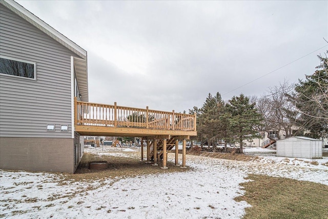 yard layered in snow with a shed and a deck