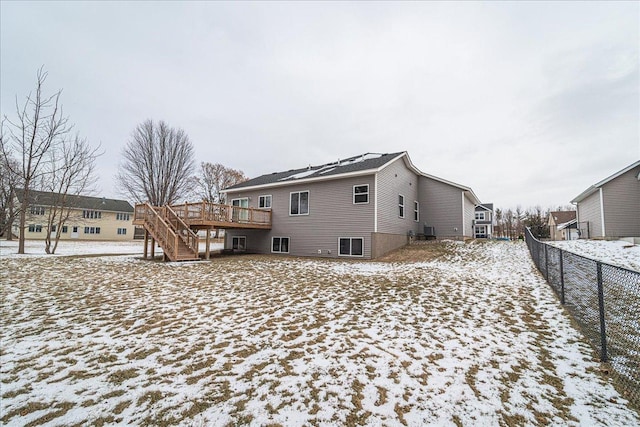 snow covered rear of property with a wooden deck