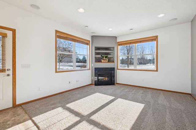 unfurnished living room with built in shelves, light carpet, and a textured ceiling