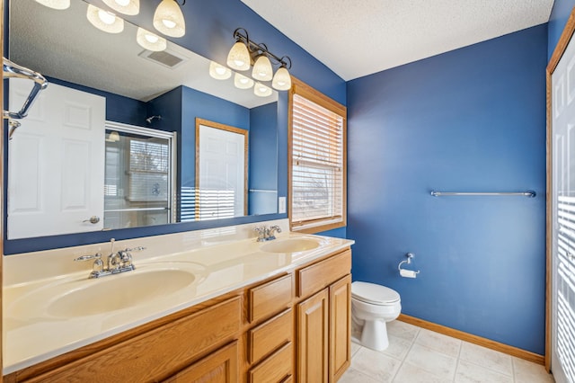 bathroom with tile patterned floors, toilet, a textured ceiling, vanity, and a shower with door