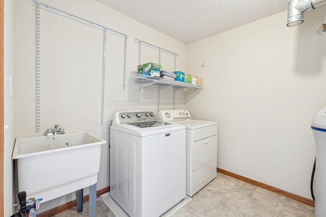 laundry area featuring washer and clothes dryer, sink, and a textured ceiling