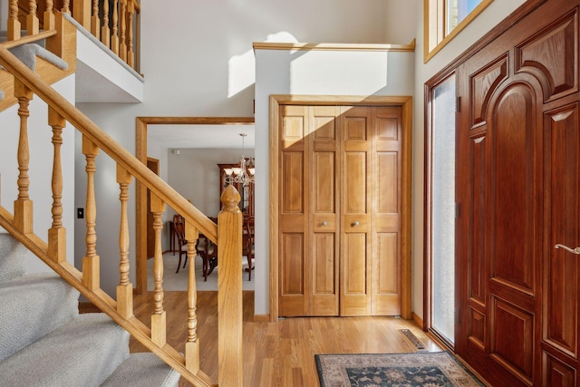 foyer with a chandelier, a high ceiling, stairs, and light wood-style flooring