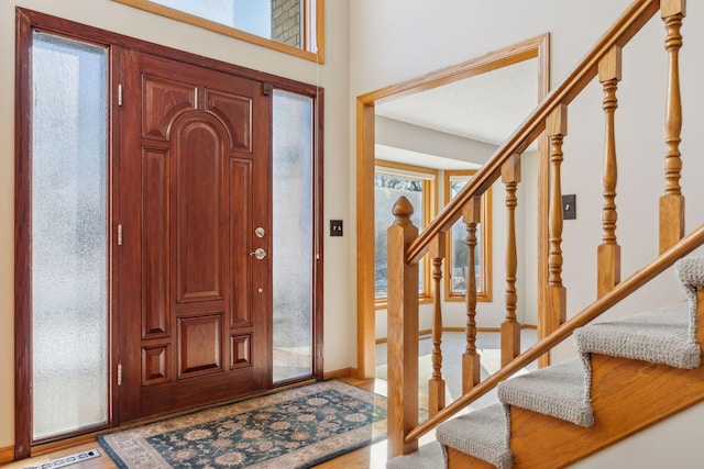 foyer entrance with visible vents, stairway, and baseboards