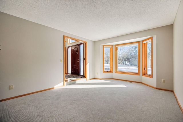 unfurnished room with light carpet, visible vents, baseboards, and a textured ceiling