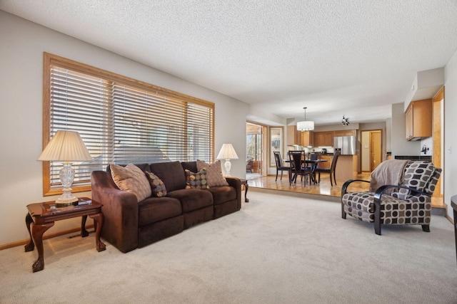 living area featuring baseboards, a textured ceiling, and light colored carpet