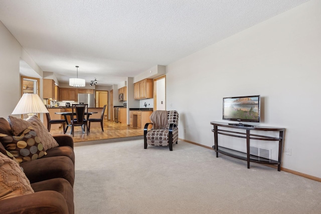 living room featuring baseboards, a textured ceiling, and light colored carpet