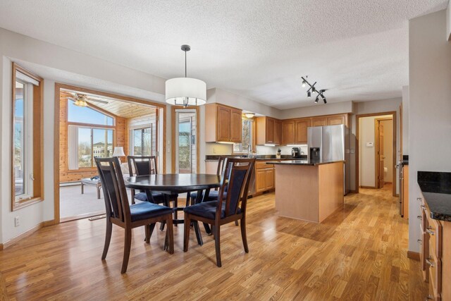 dining space featuring a textured ceiling, light wood-style flooring, and baseboards