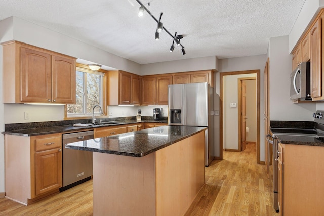 kitchen featuring a sink, appliances with stainless steel finishes, a kitchen island, and light wood-style flooring