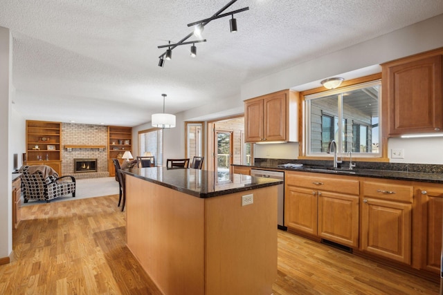 kitchen featuring open floor plan, a brick fireplace, a center island, dishwasher, and pendant lighting