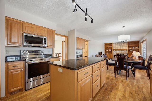 kitchen featuring a center island, pendant lighting, light wood-style flooring, appliances with stainless steel finishes, and brown cabinetry