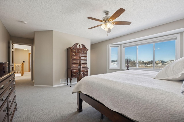 bedroom featuring light colored carpet, ceiling fan, a textured ceiling, and baseboards