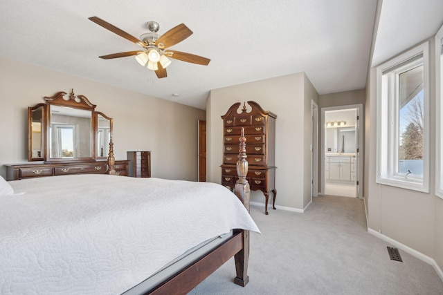 bedroom featuring light carpet, a ceiling fan, visible vents, baseboards, and ensuite bath