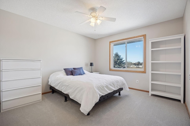 bedroom with a ceiling fan, baseboards, a textured ceiling, and light colored carpet