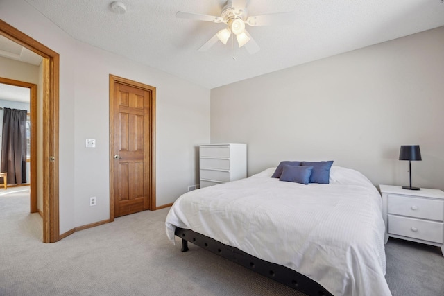 bedroom with a ceiling fan, light colored carpet, a textured ceiling, and baseboards