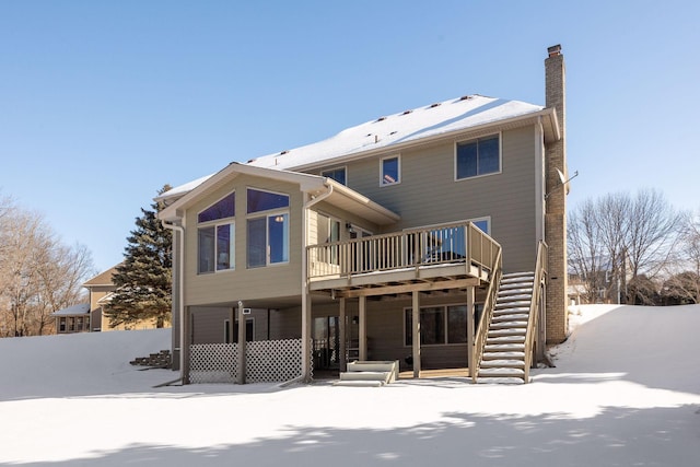 snow covered rear of property with stairs, a chimney, and a deck