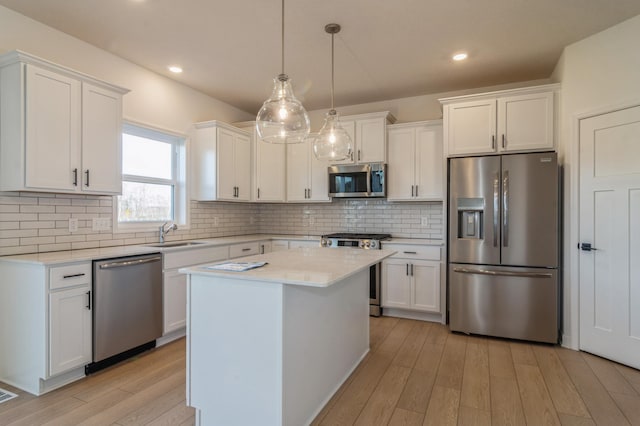 kitchen featuring white cabinetry, hanging light fixtures, stainless steel appliances, a center island, and light wood-type flooring