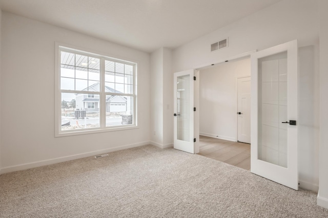 unfurnished bedroom with light carpet and french doors