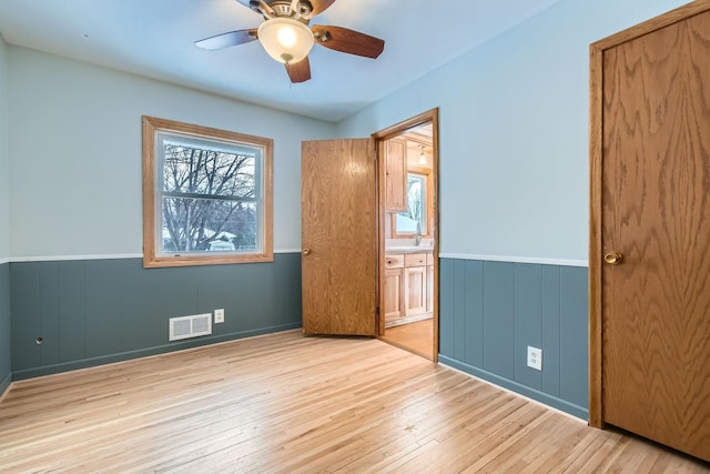 unfurnished bedroom with ensuite bathroom, ceiling fan, and light hardwood / wood-style flooring