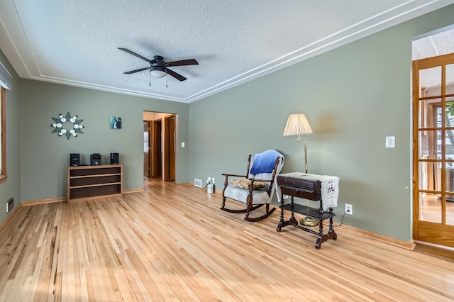 living area with ceiling fan, light hardwood / wood-style flooring, and a textured ceiling