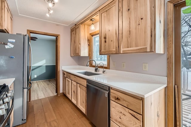 kitchen featuring stainless steel appliances, light brown cabinetry, sink, and light wood-type flooring