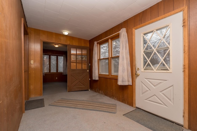 doorway featuring light colored carpet and wood walls