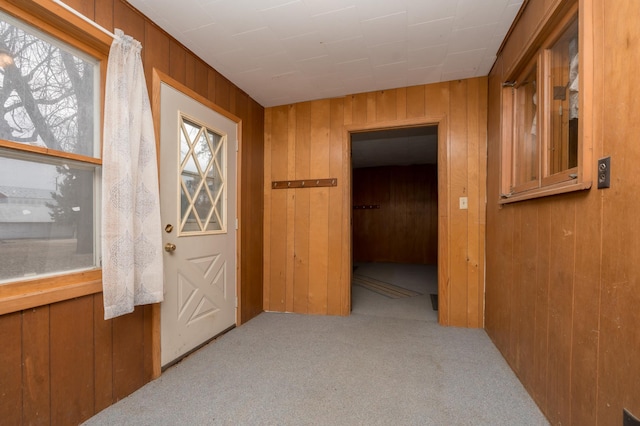 hall featuring light colored carpet and wooden walls