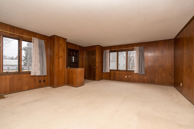 unfurnished living room with wooden walls and light colored carpet