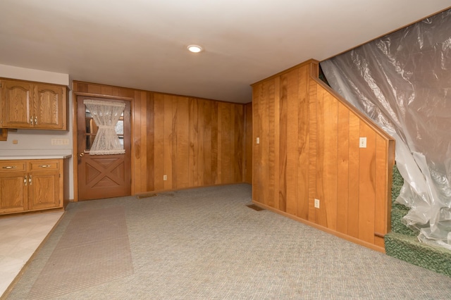 interior space featuring light carpet and wood walls