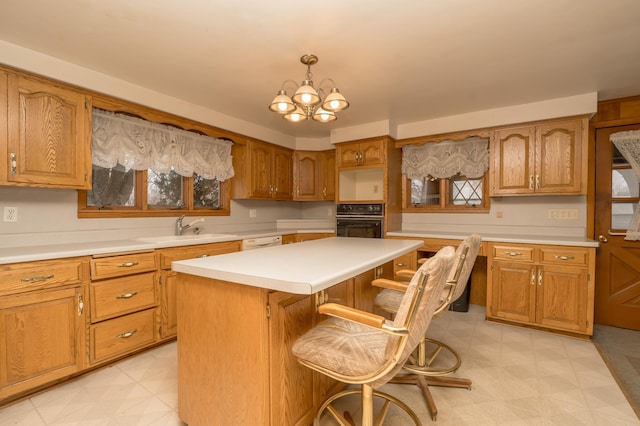 kitchen featuring sink, a breakfast bar area, a kitchen island, pendant lighting, and oven