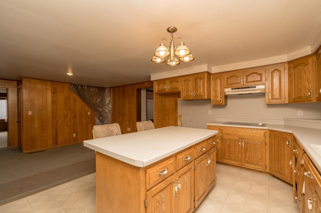 kitchen with decorative light fixtures, a chandelier, a center island, wooden walls, and black electric stovetop