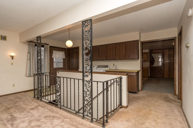 interior space featuring dark brown cabinetry, hanging light fixtures, and light carpet