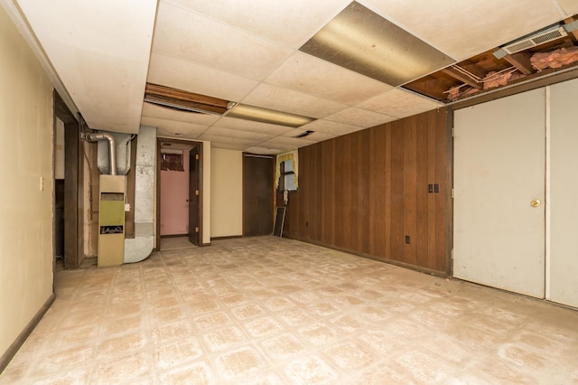 basement featuring wooden walls and a paneled ceiling