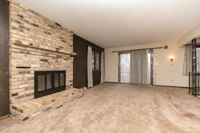 unfurnished living room featuring carpet and a brick fireplace