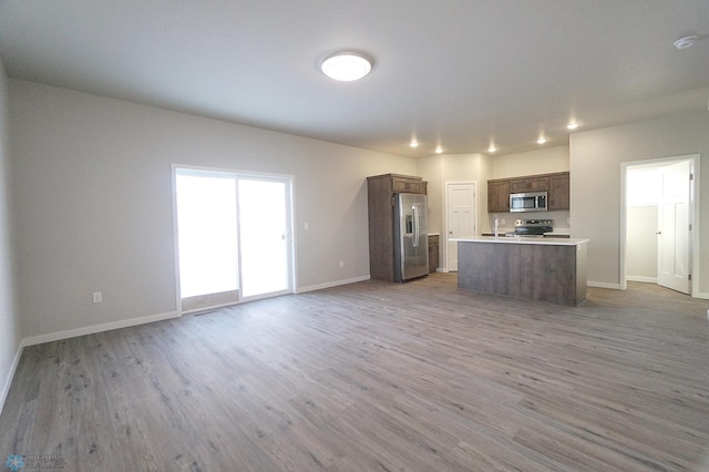 kitchen with a kitchen island, appliances with stainless steel finishes, and hardwood / wood-style flooring