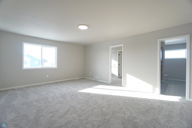 6020 80th Ave S, Fargo, ND 58047 - unfurnished bedroom with light colored carpet, multiple windows, baseboards, and connected bathroom