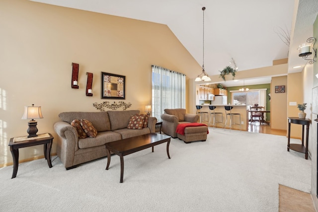 living room with a chandelier, light colored carpet, and high vaulted ceiling