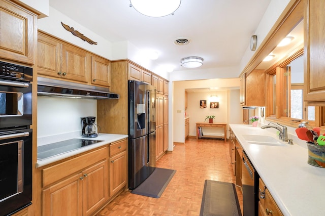 kitchen featuring under cabinet range hood, a sink, visible vents, light countertops, and black appliances