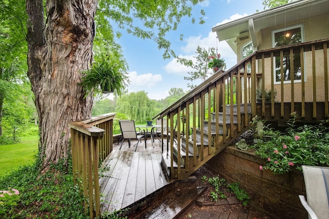 wooden terrace featuring stairs, a yard, and outdoor dining area