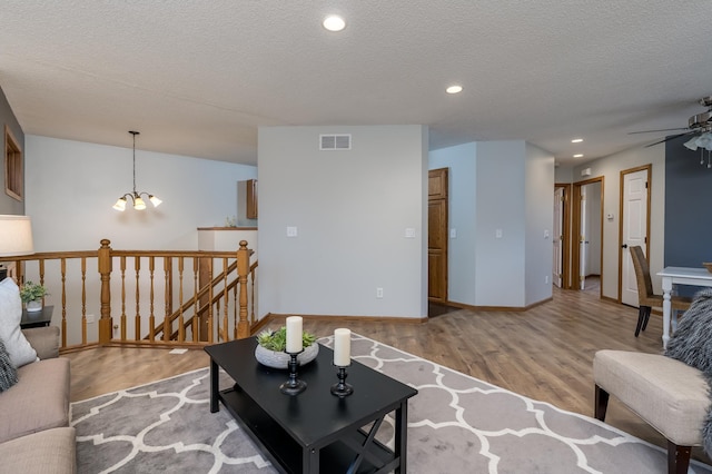 living room featuring a textured ceiling, light hardwood / wood-style flooring, and a chandelier