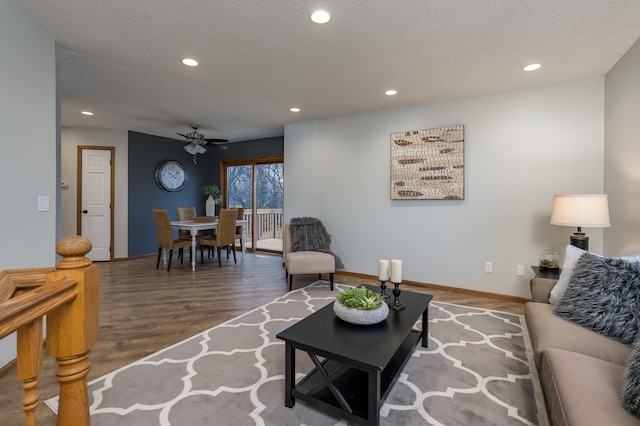 living room featuring ceiling fan, hardwood / wood-style floors, and a textured ceiling