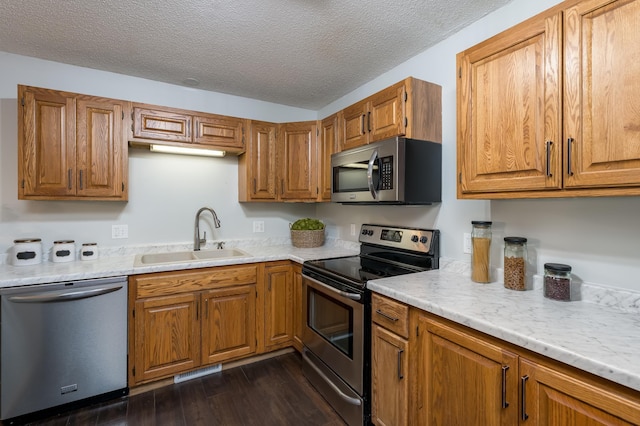 kitchen with sink, dark wood-type flooring, stainless steel appliances, and a textured ceiling