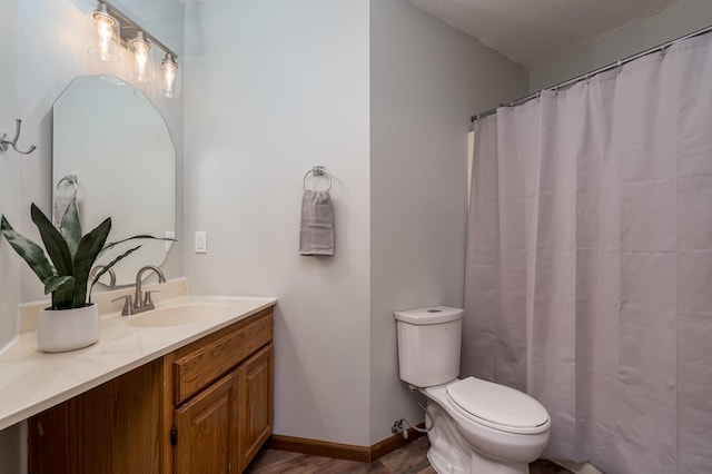 bathroom featuring vanity, hardwood / wood-style floors, a textured ceiling, and toilet