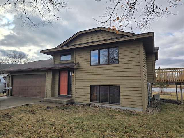 tri-level home with cooling unit, a garage, and a front yard