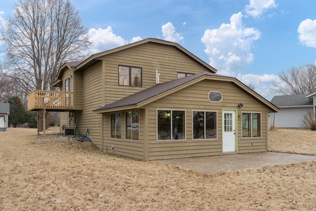 back of house with cooling unit, a wooden deck, and a patio